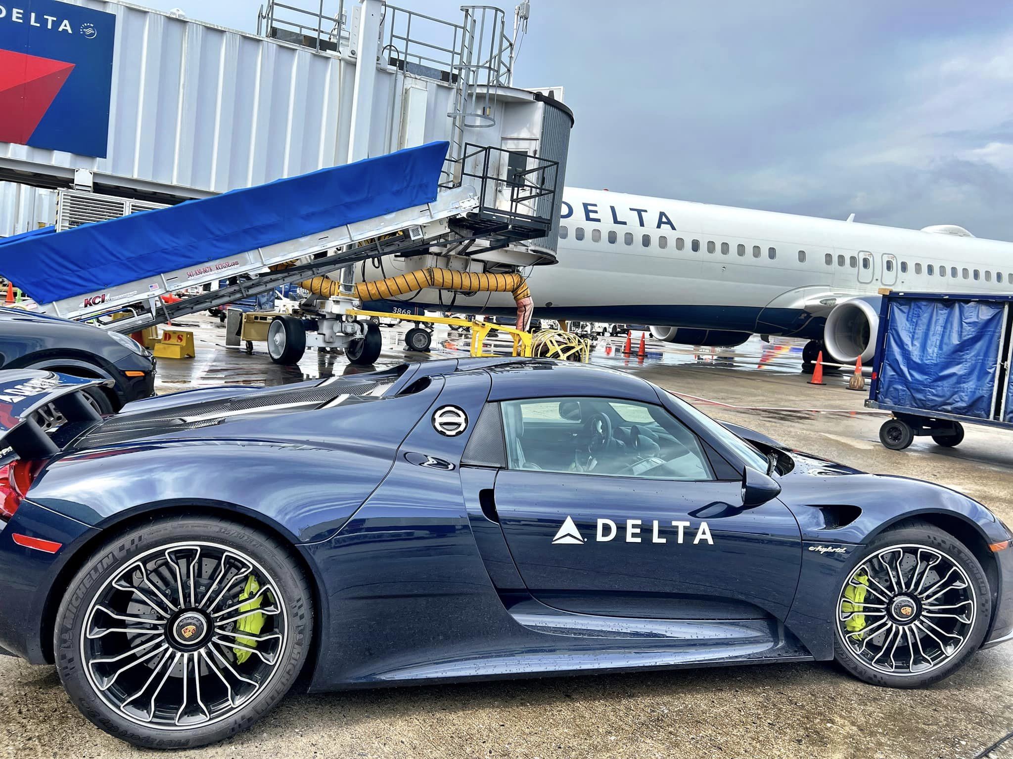 a blue sports car parked next to a plane