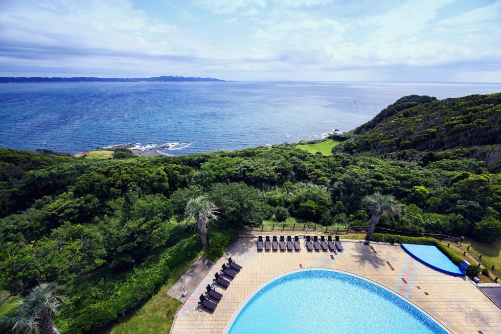 a pool with chairs and trees by the water