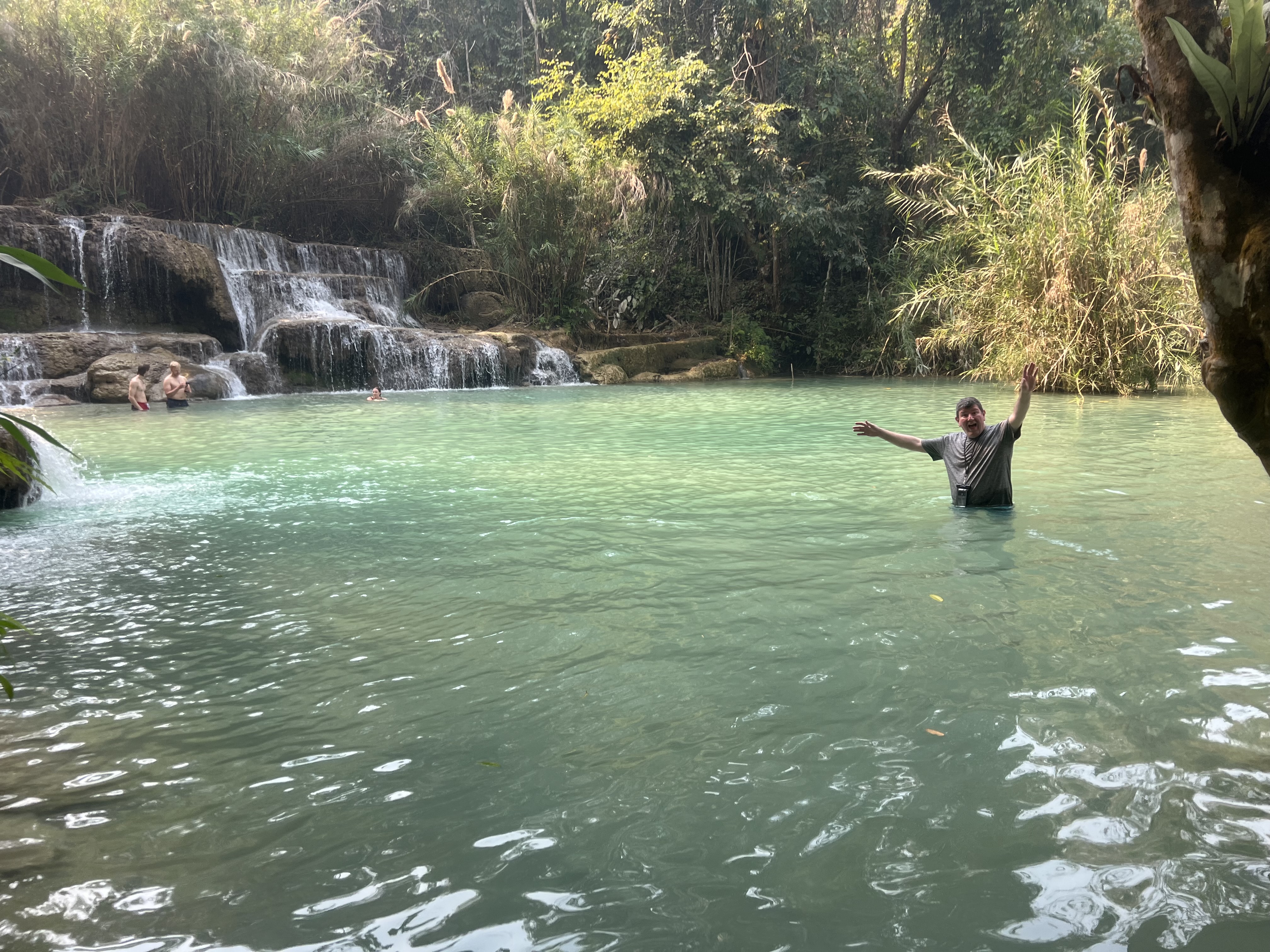 a man standing in a body of water with his arms raised