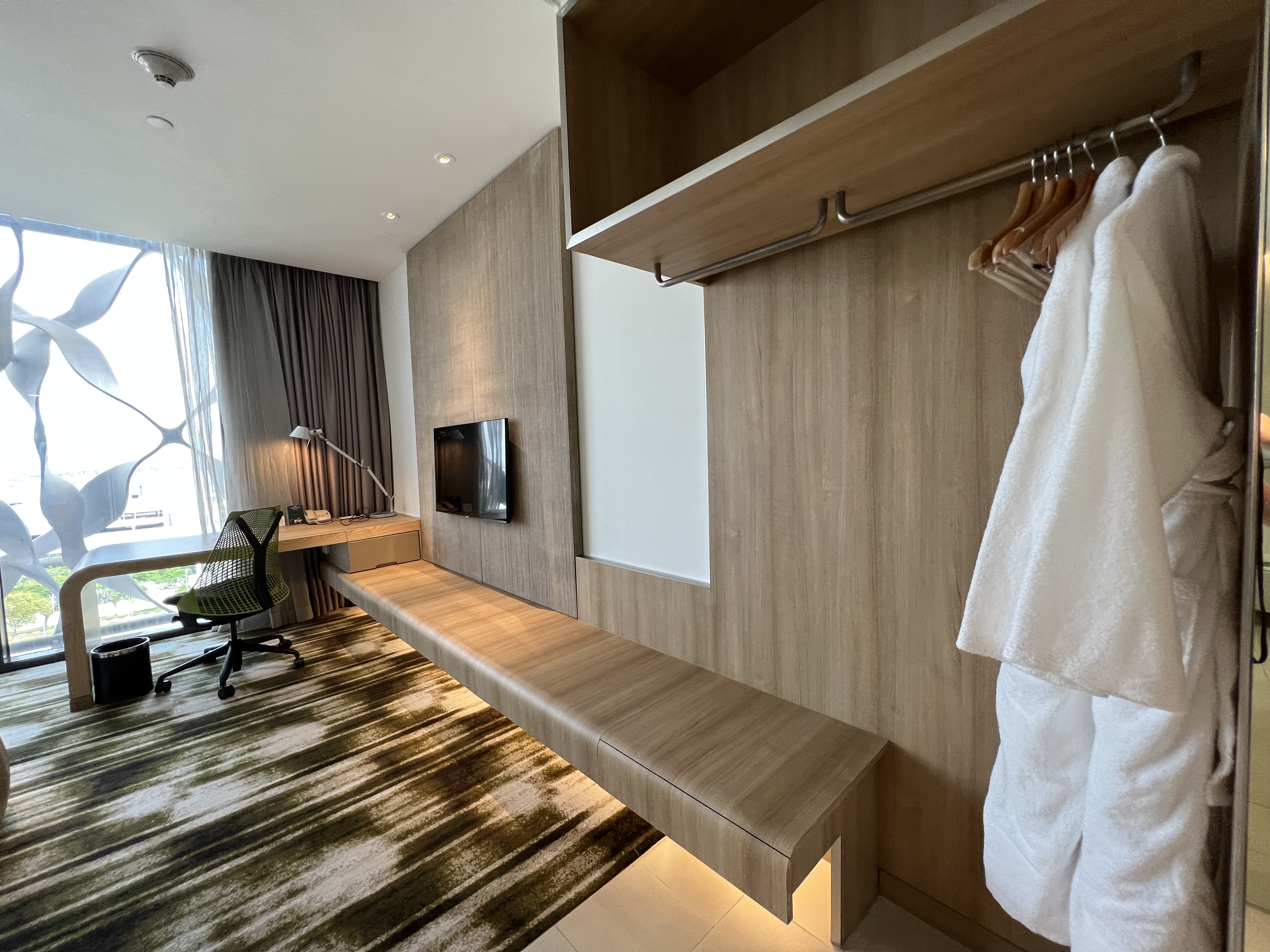 a room with a tv and a white robe on a rack