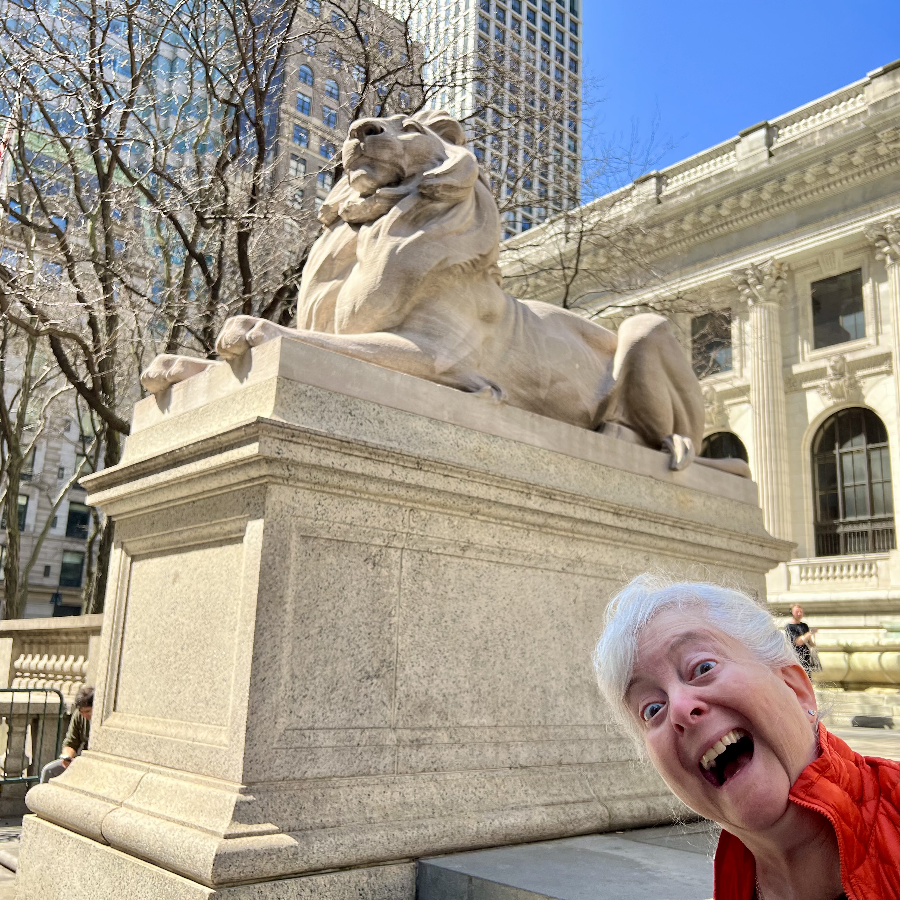 a woman taking a selfie with a lion statue in front of a building