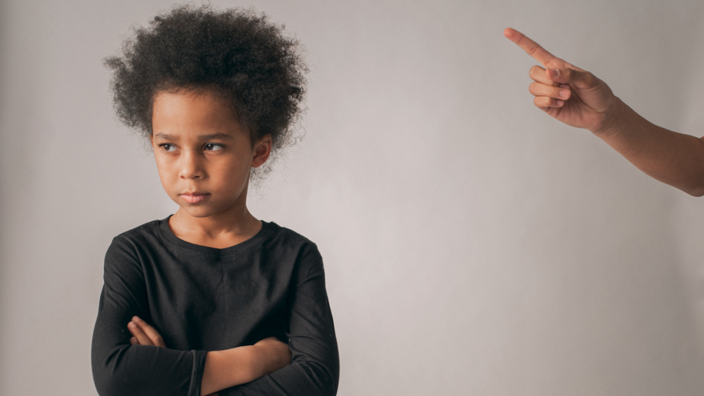 a child with her arms crossed and a hand pointing to the side