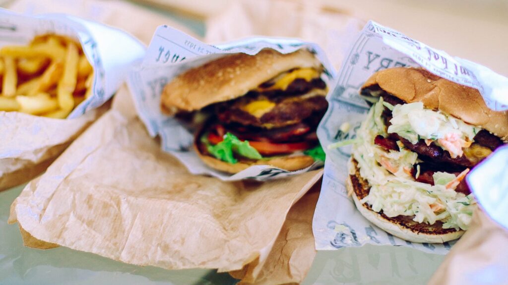 two burgers in wrappers on a table