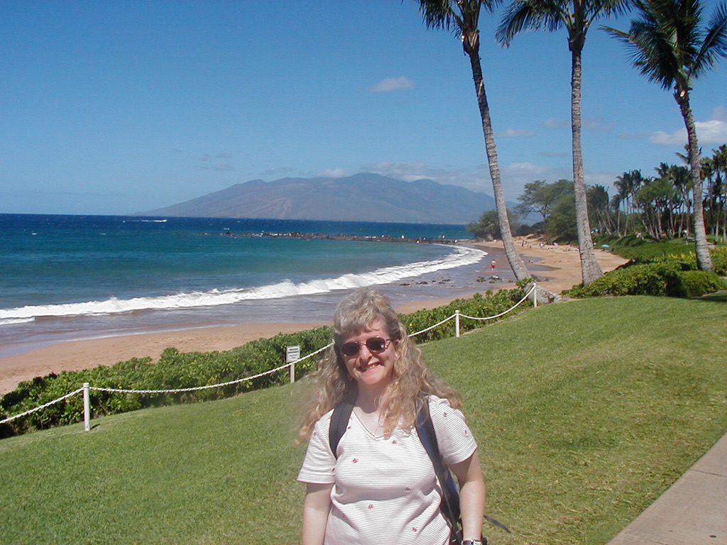 a woman standing on a grassy hill next to a beach