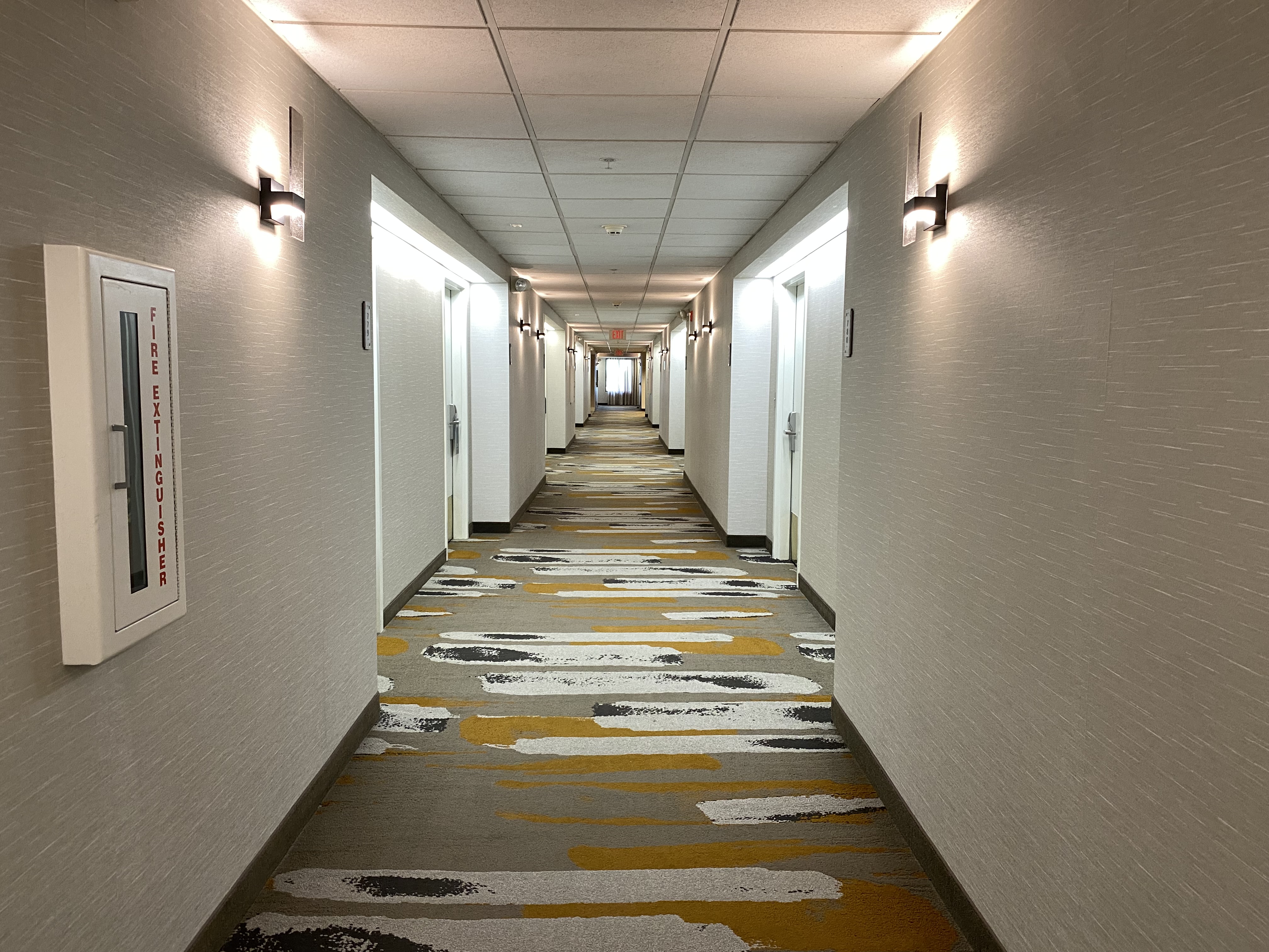 a long hallway with white walls and colorful carpet