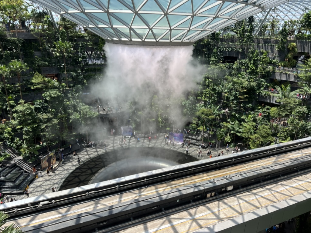 a large indoor fountain with trees and people