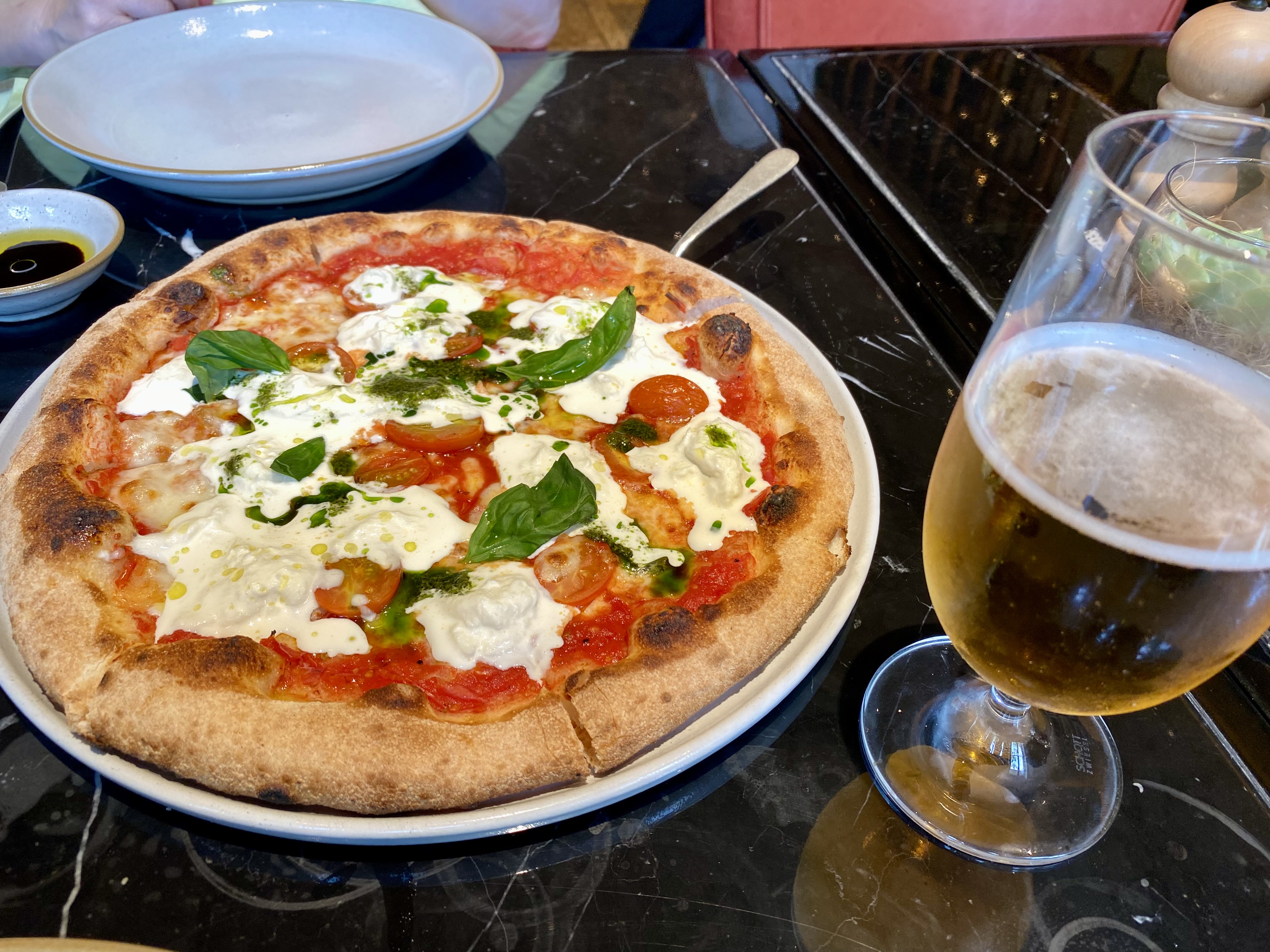a pizza on a plate next to a glass of beer