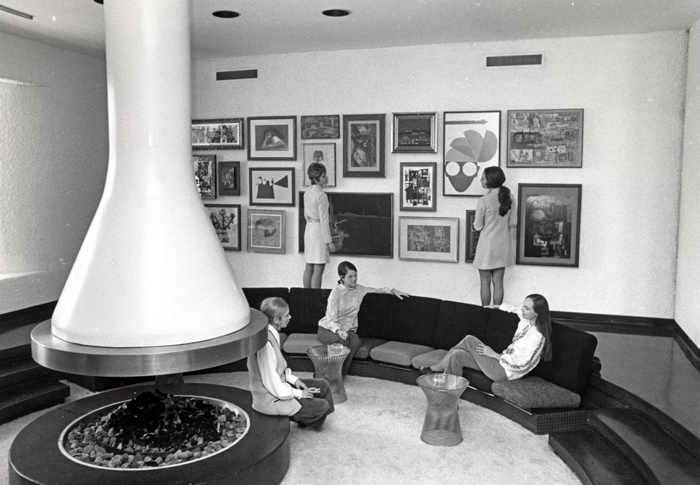 a group of women sitting on a couch in a room with art on the wall