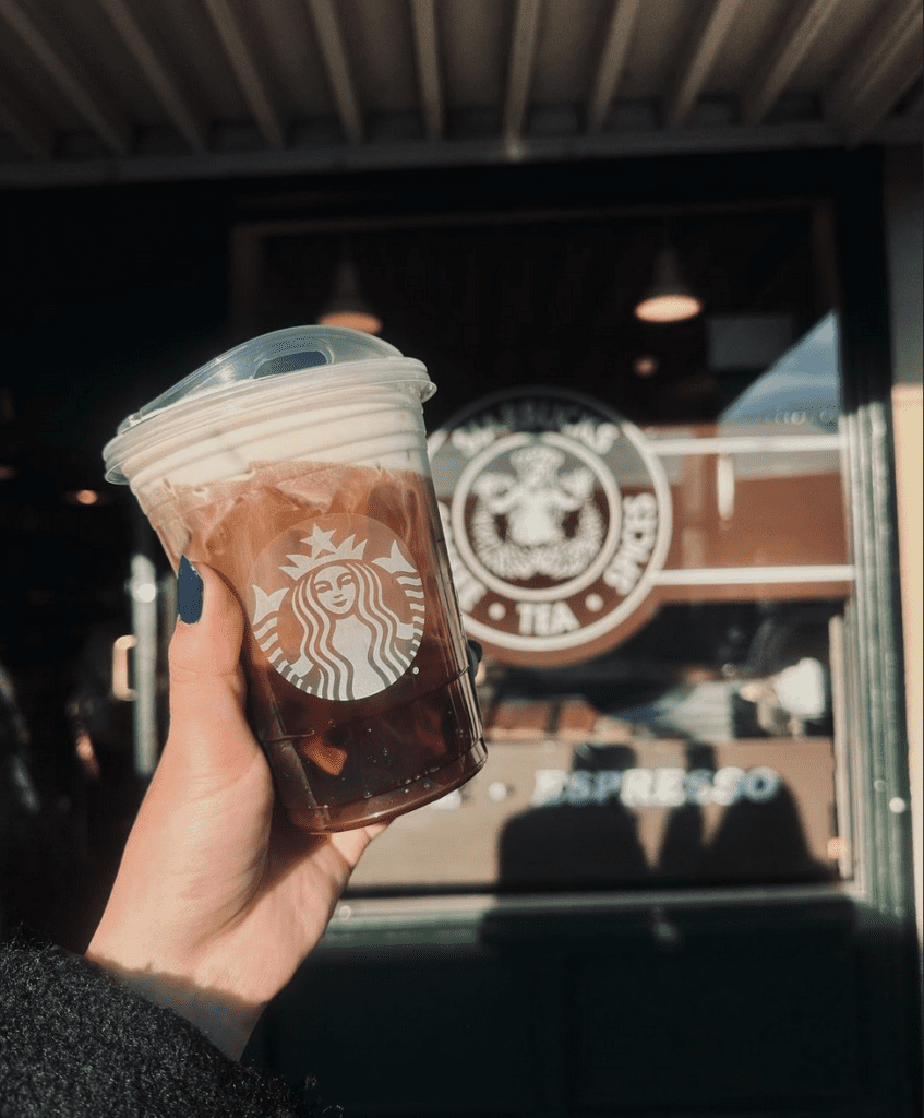 a hand holding a plastic cup of iced coffee