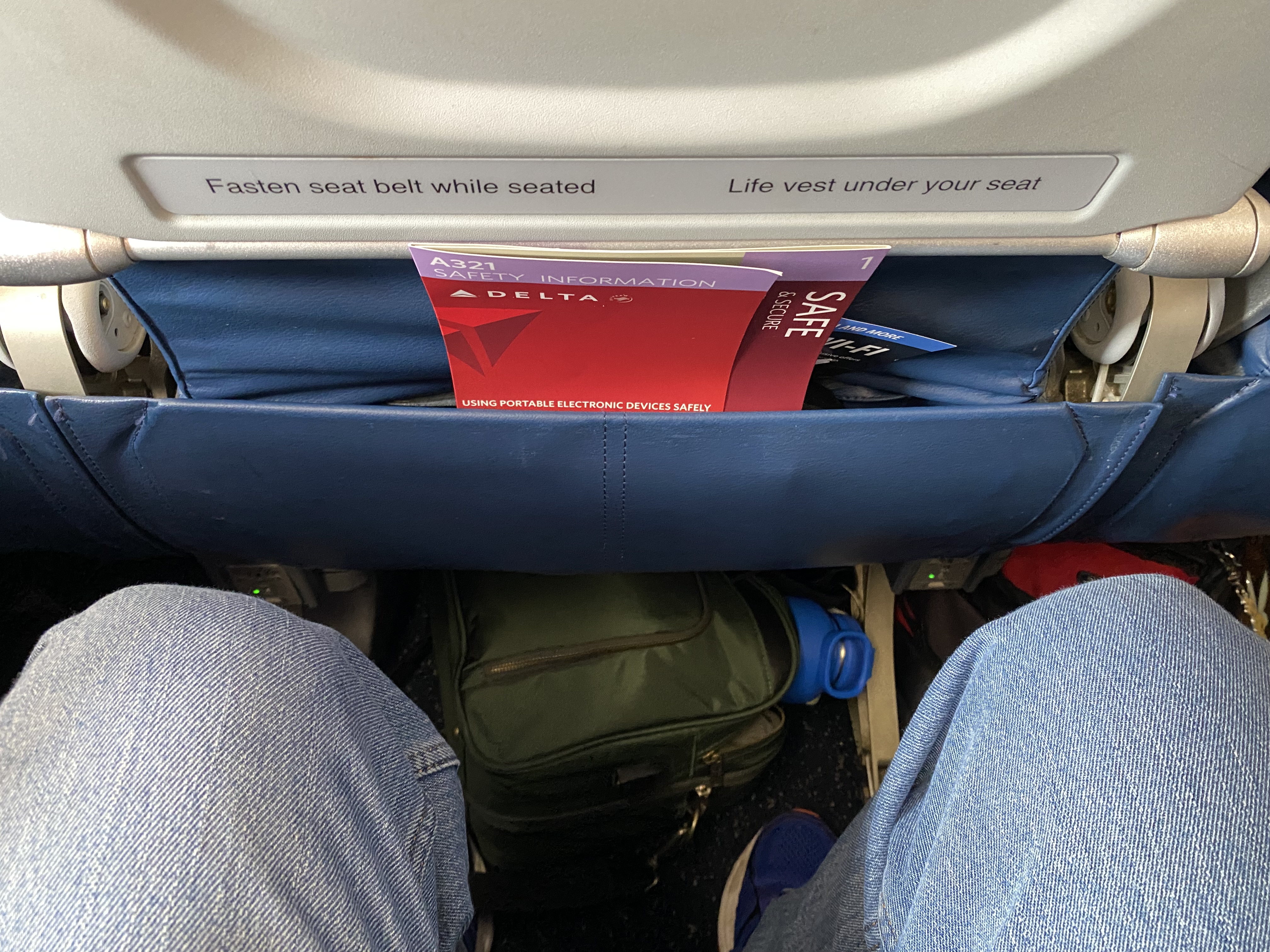 a seat belt with a sign and luggage in the back of a plane