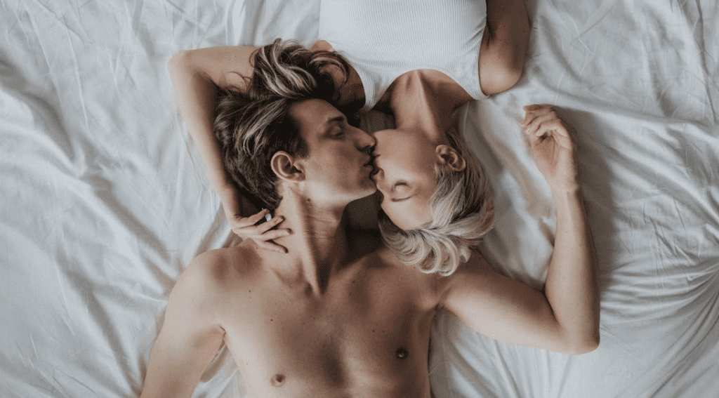 a man and woman lying on a bed kissing