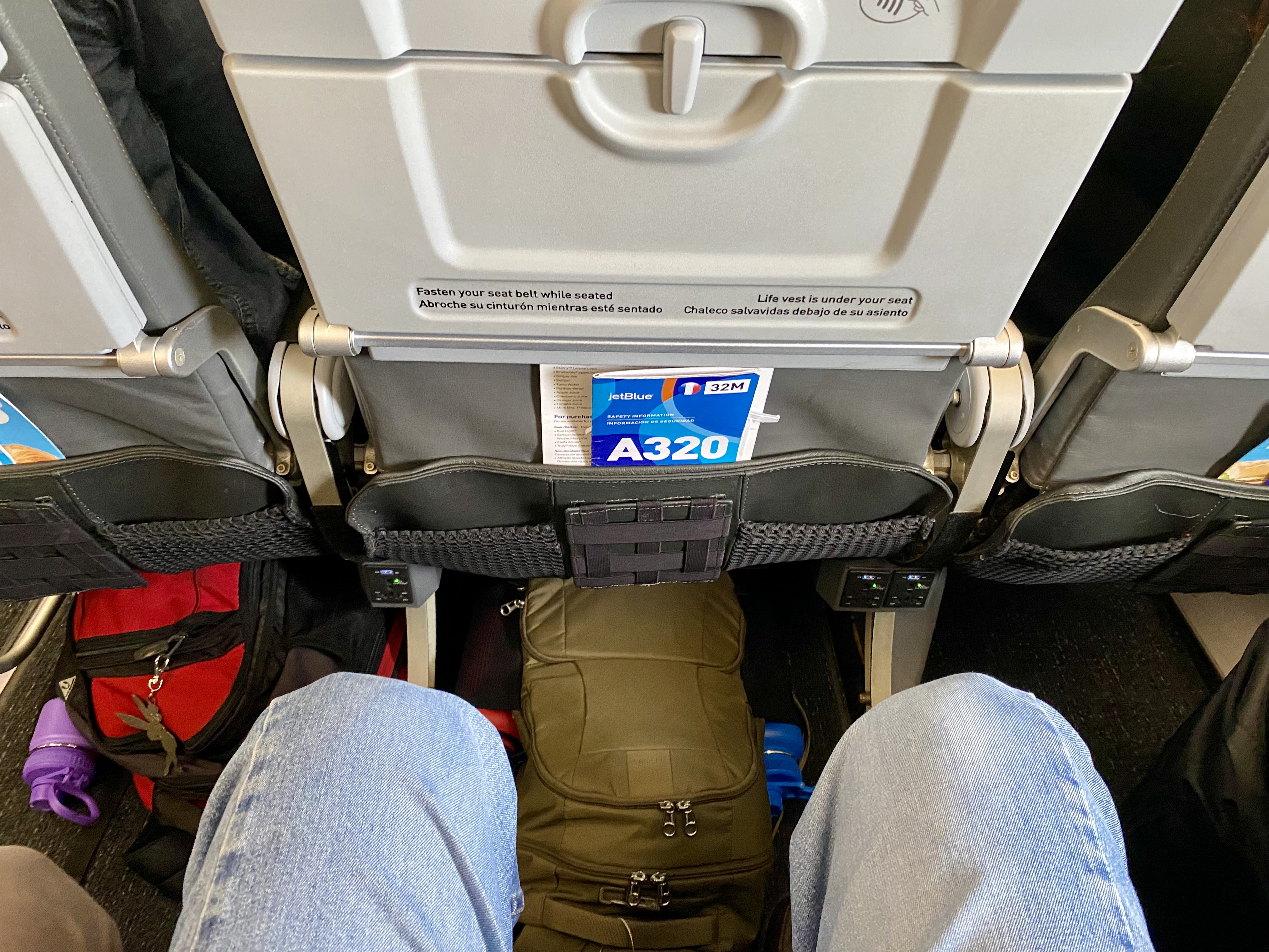 a person's legs and a backpack in an airplane