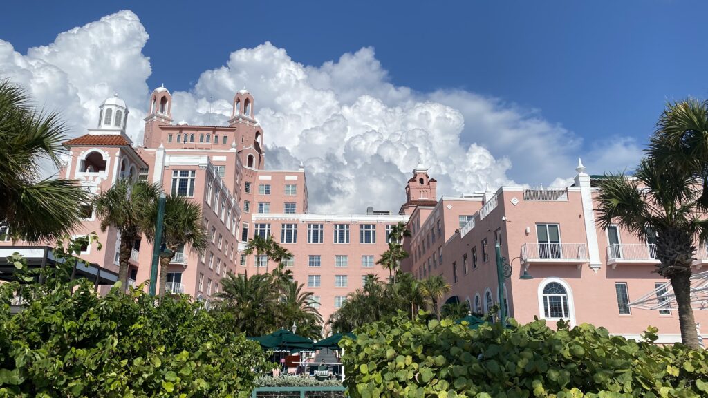 a large pink building with trees and blue sky