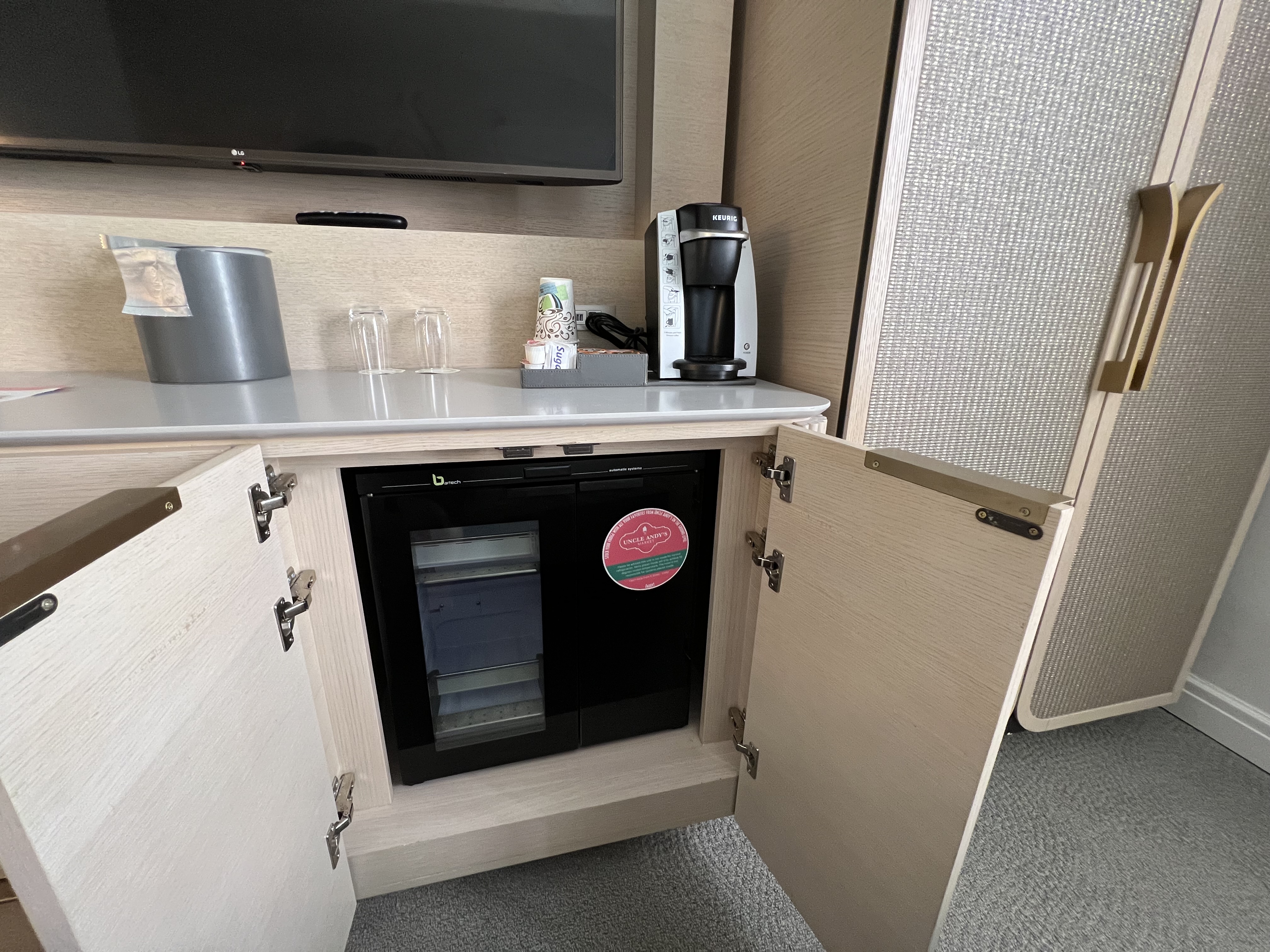 a small kitchen with a small black refrigerator and a coffee maker