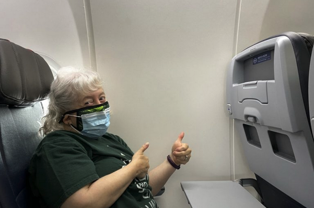 a woman wearing a mask and giving thumbs up