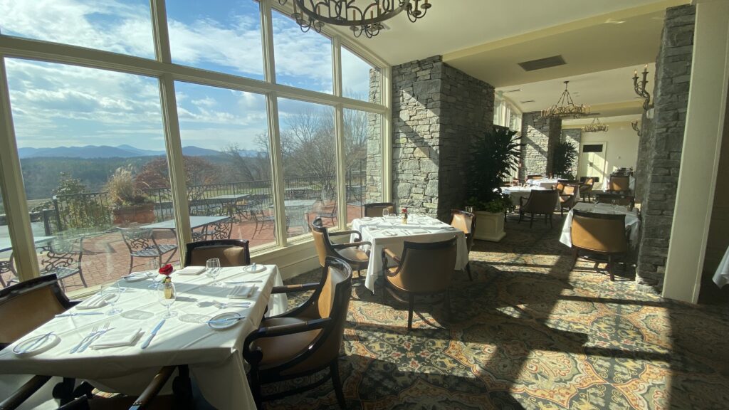 a room with tables and chairs and a large window