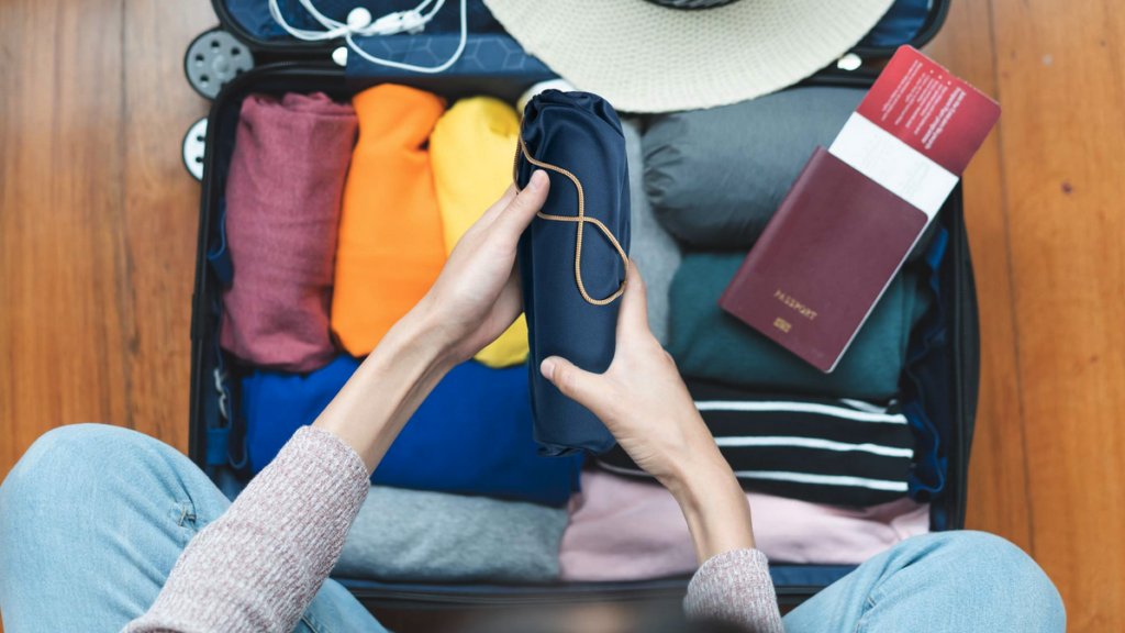 a person holding a rolled up blue object in a suitcase