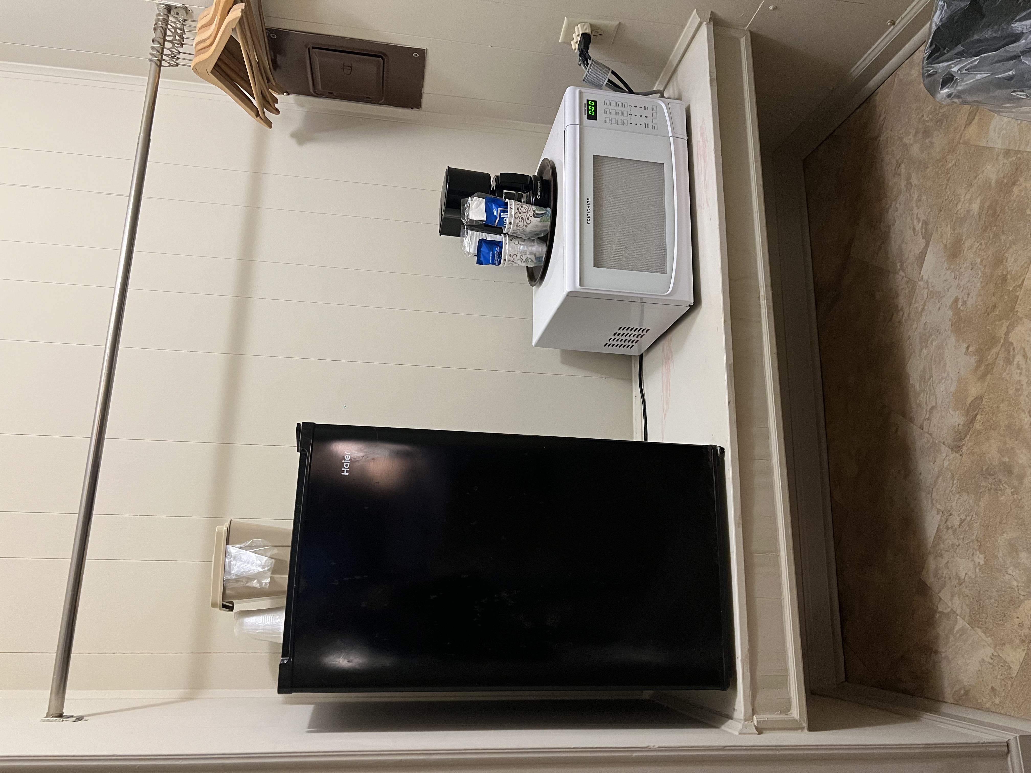 a black refrigerator and a microwave on a white shelf