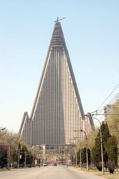 a tall building with a triangular roof with Ryugyong Hotel in the background