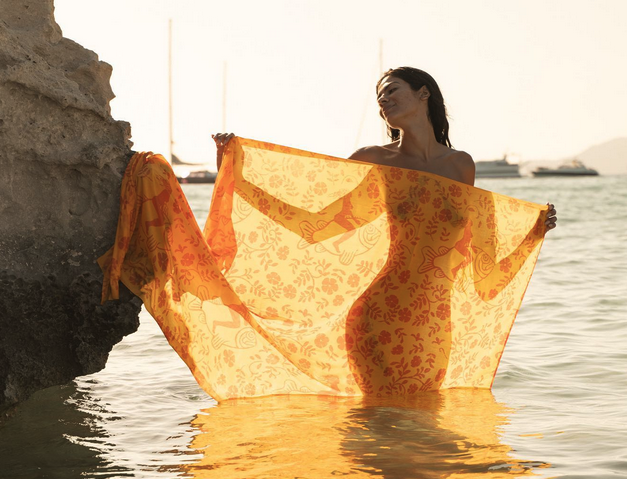 a woman holding a yellow scarf in the water