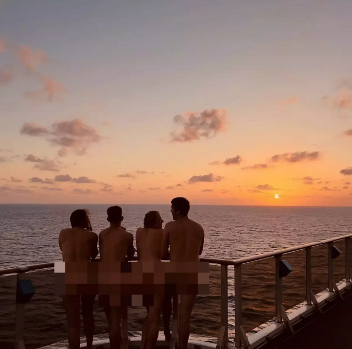 a group of people standing on a railing overlooking the ocean
