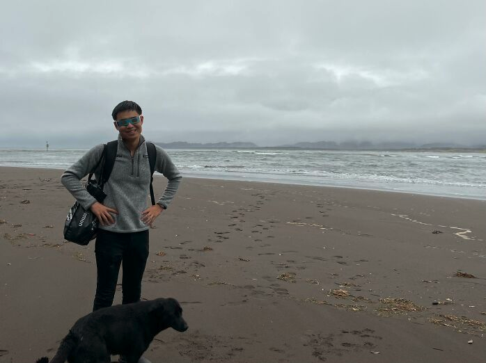 a man standing on a beach with a dog