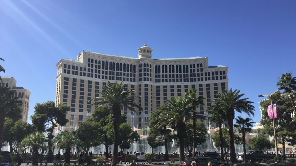 a large building with many windows and a fountain in front with Bellagio in the background