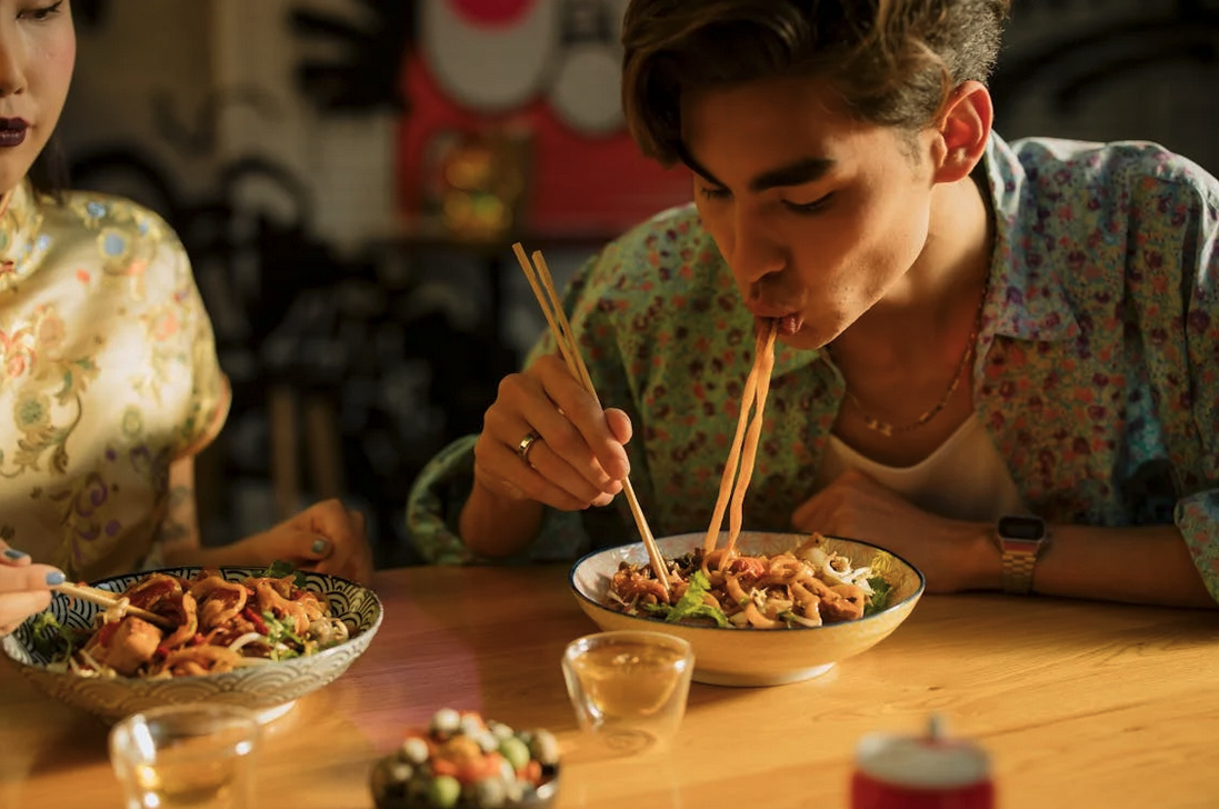 a man eating noodles with chopsticks