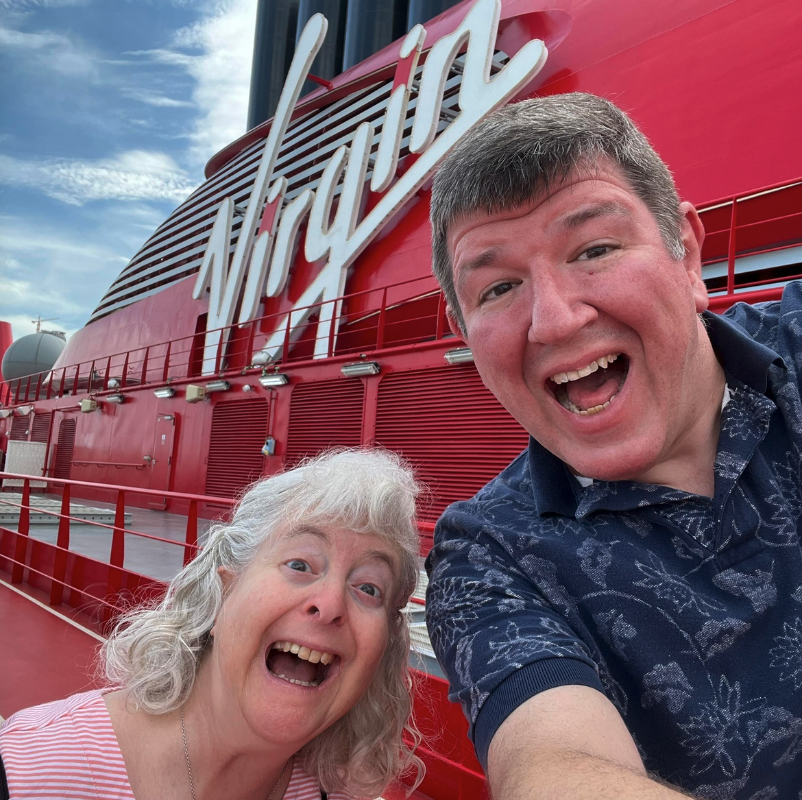 a man and woman taking a selfie in front of a red ship