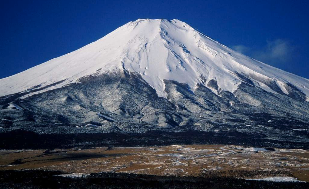 a snow covered mountain top with Mount Fuji in the background