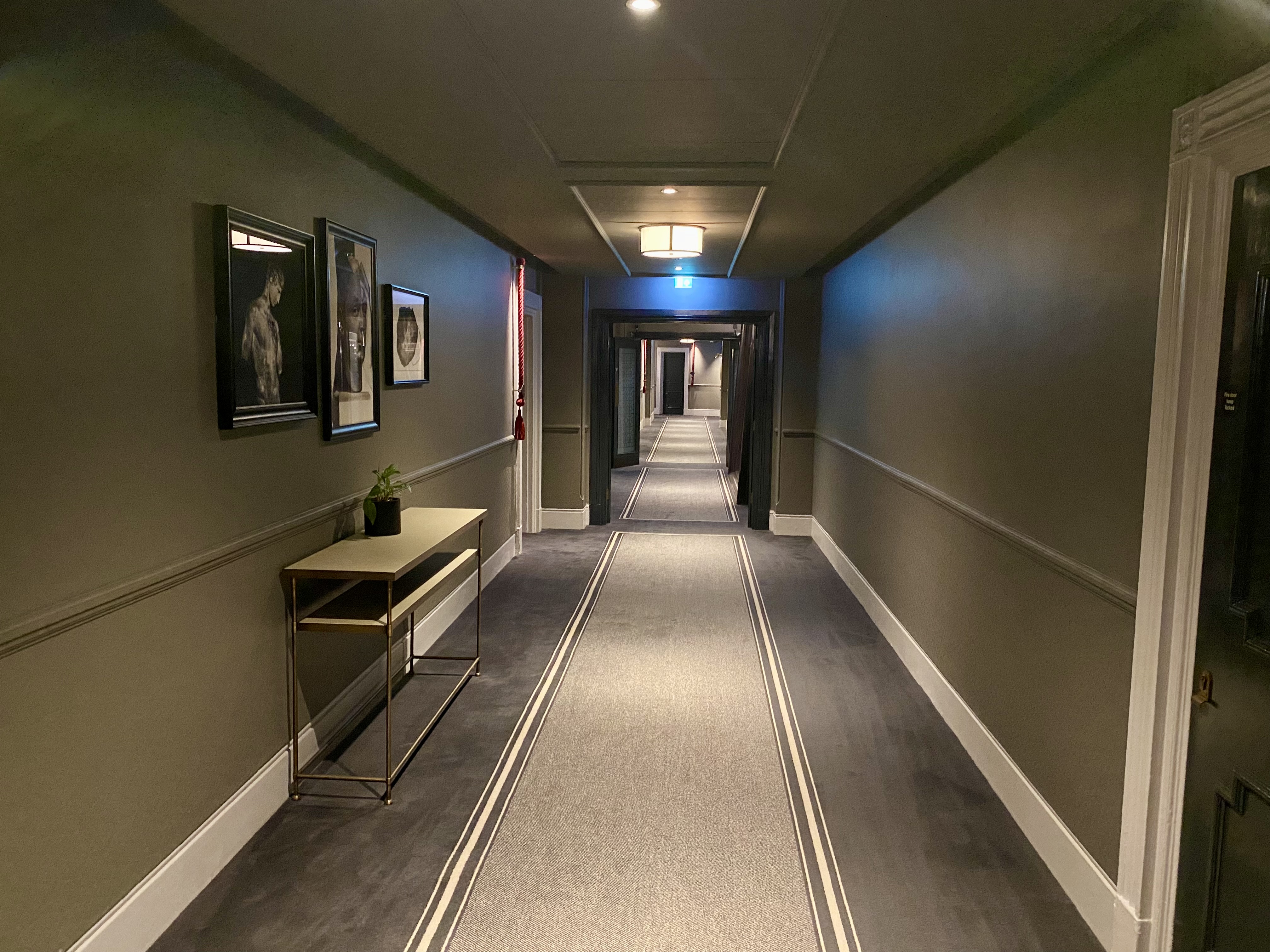 a hallway with a table and pictures on the wall