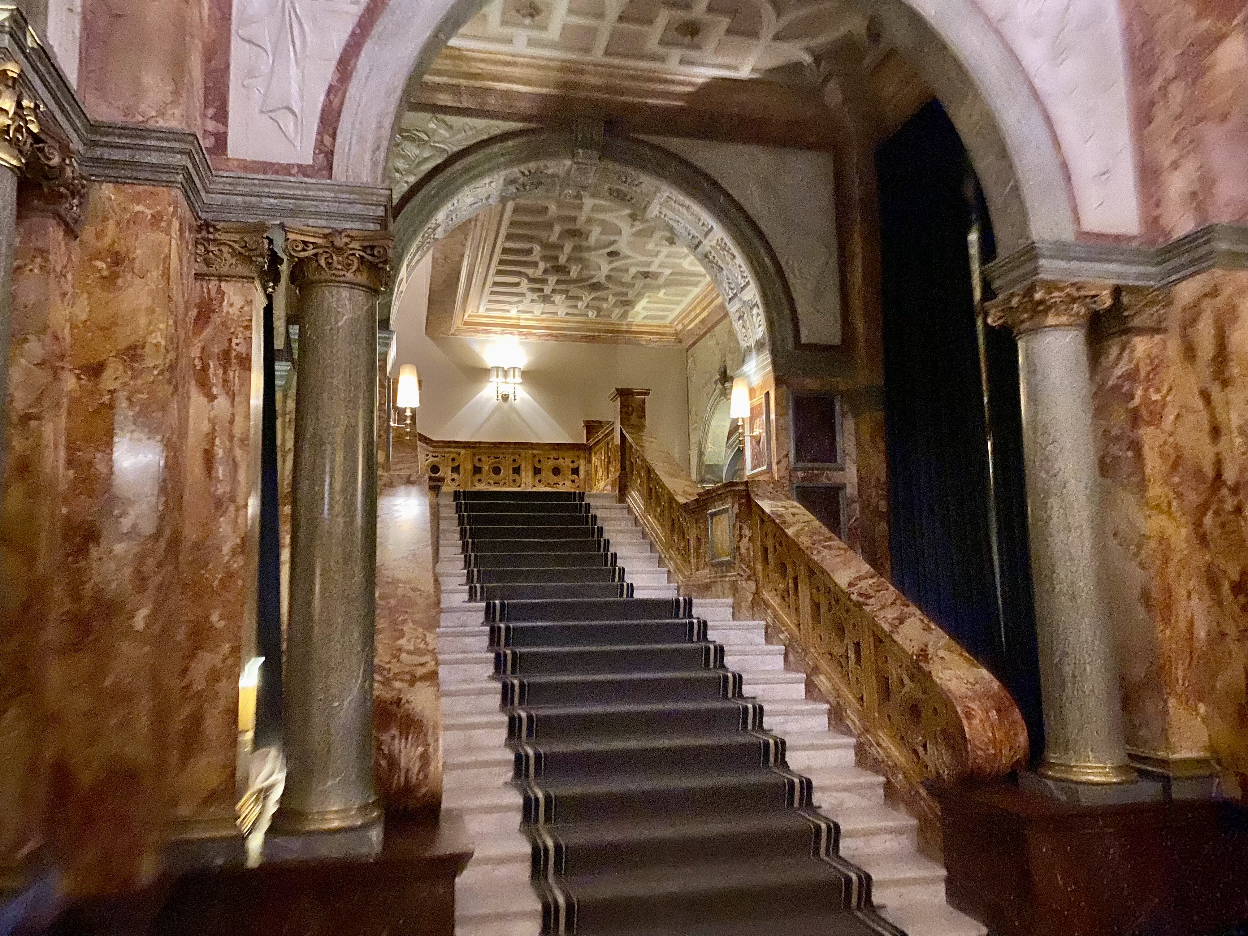 a staircase with black carpet and a stone railing