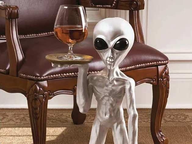 a alien statue holding a glass of wine