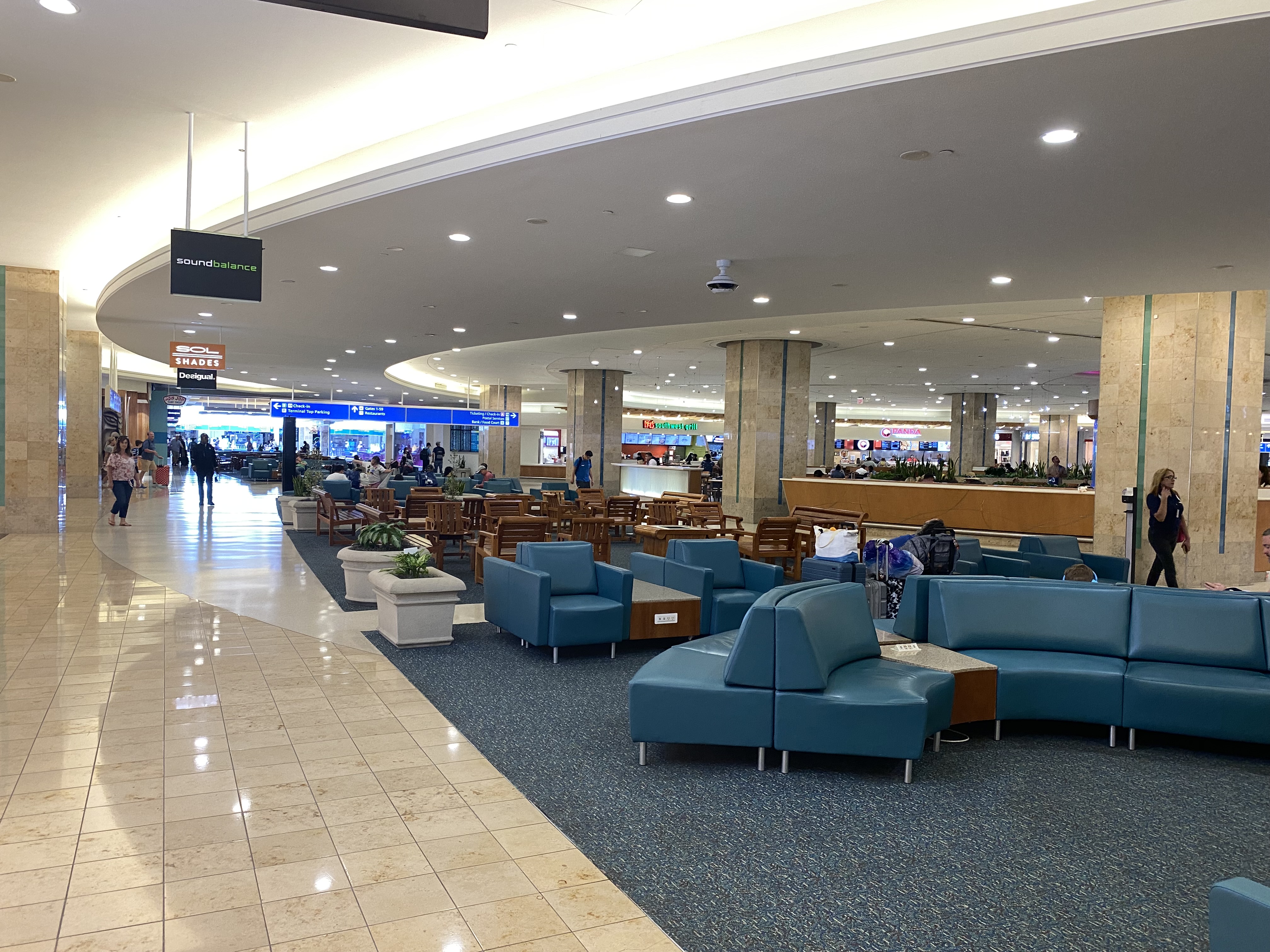 a large airport terminal with blue chairs and tables
