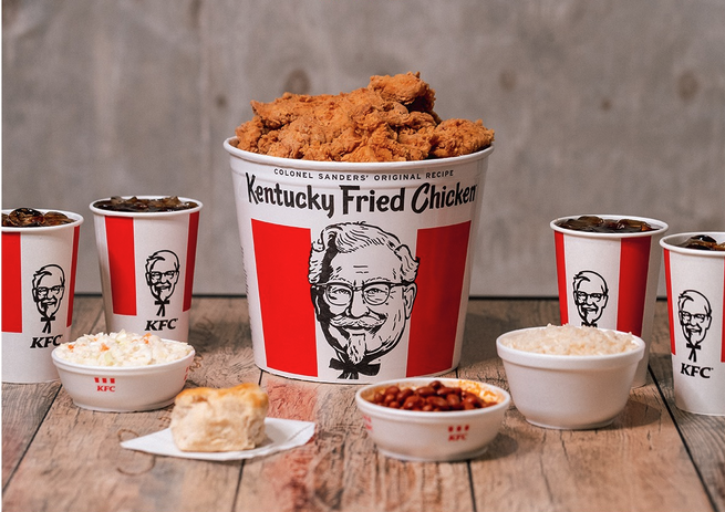 a bucket of fried chicken and different types of food