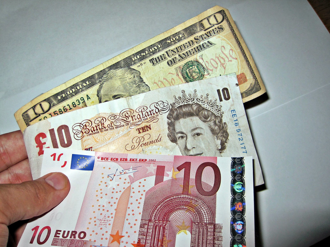 a hand holding money next to a dollar bill