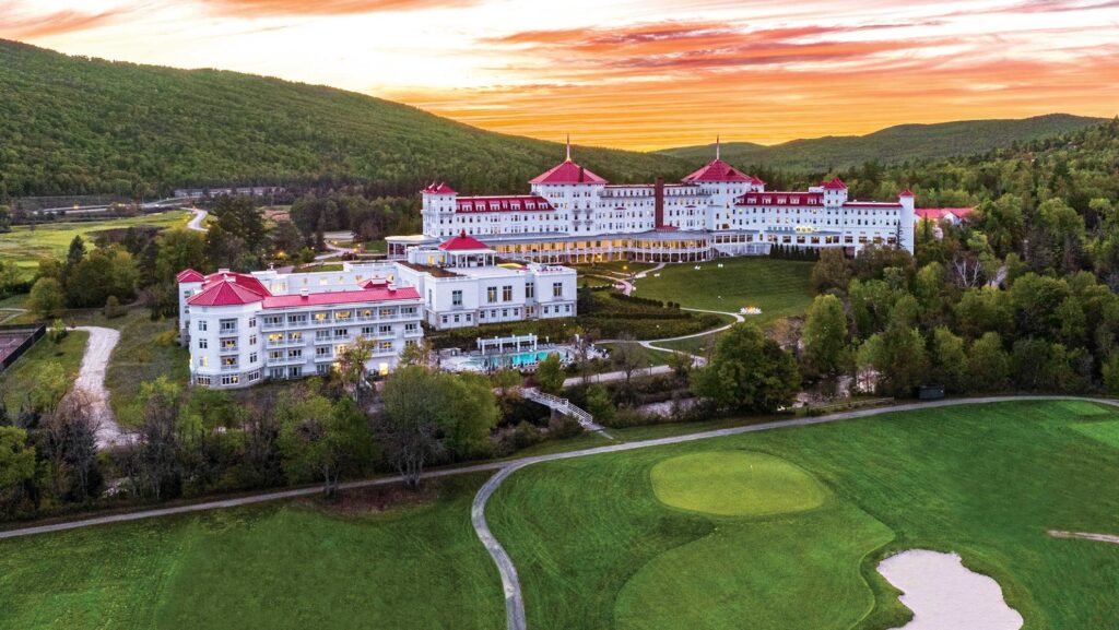 a large white building with red roofs and a golf course