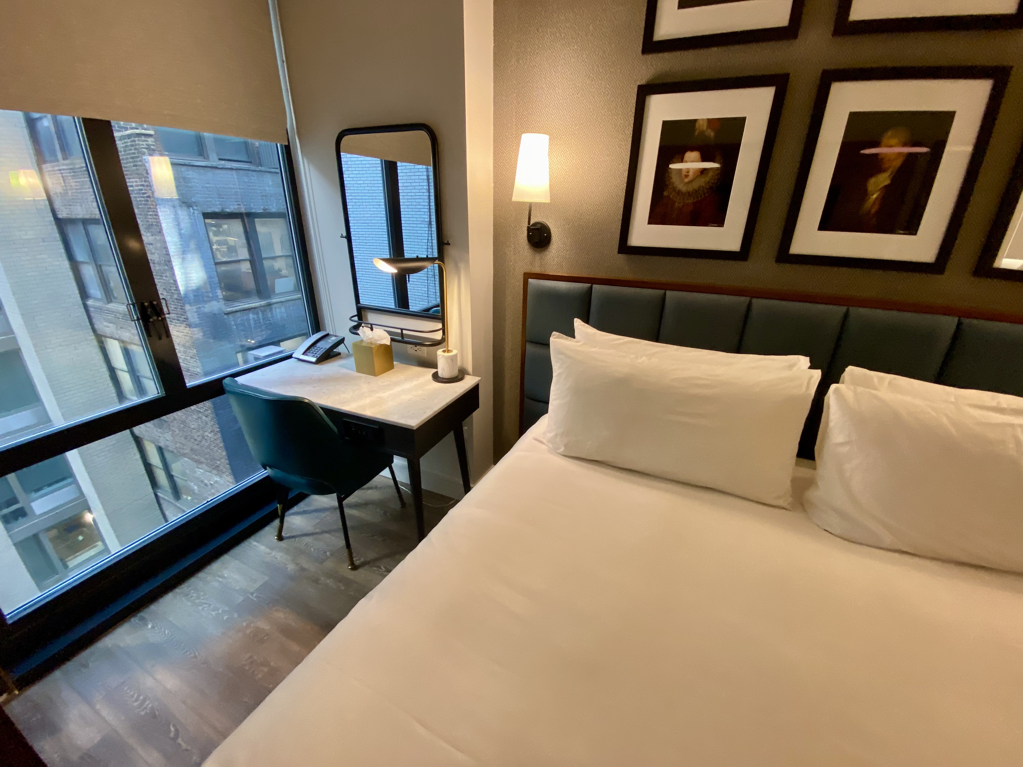 a bed with white pillows and a desk in a hotel room