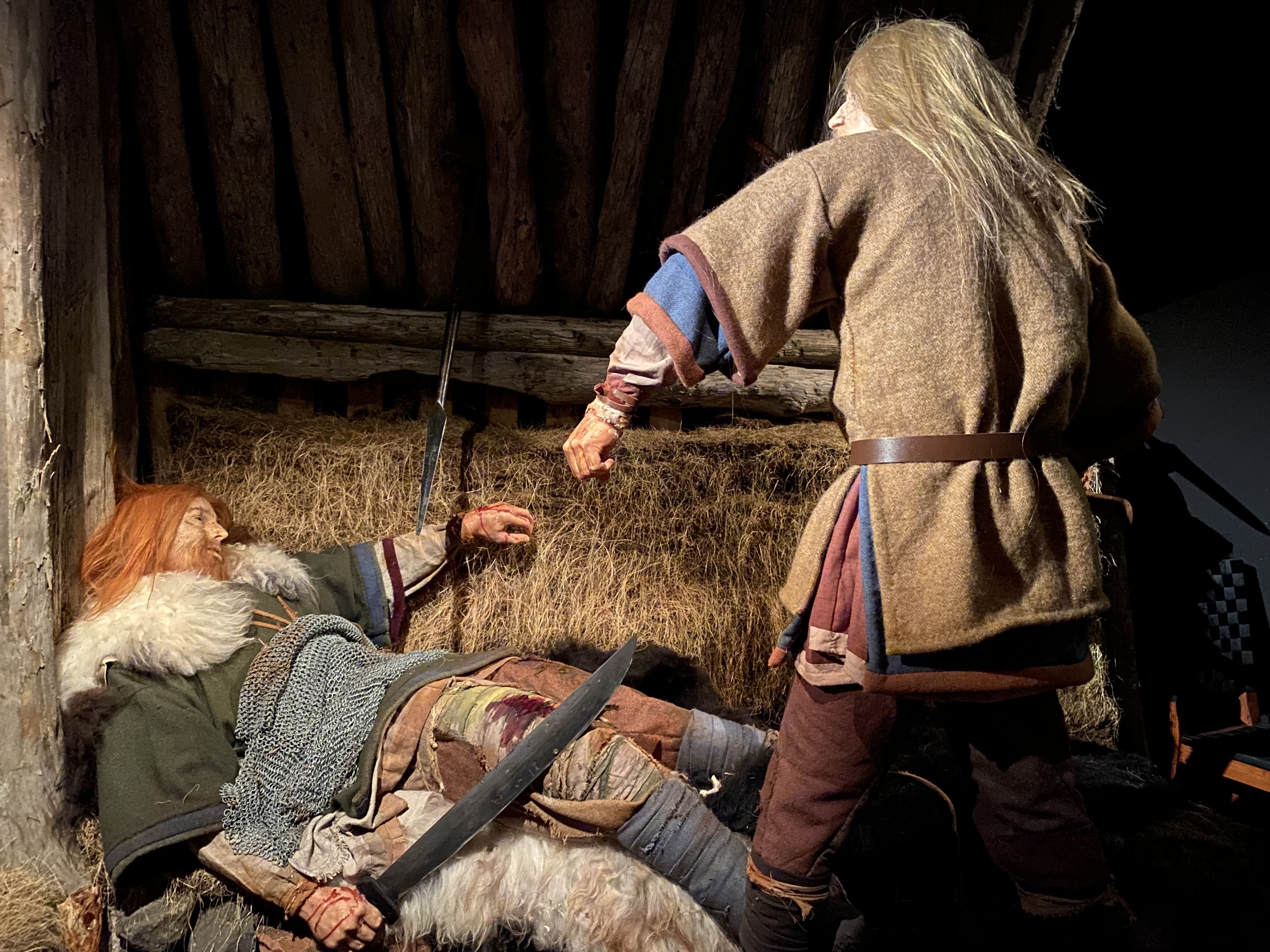 a man in a garment holding a sword to a man lying on the ground