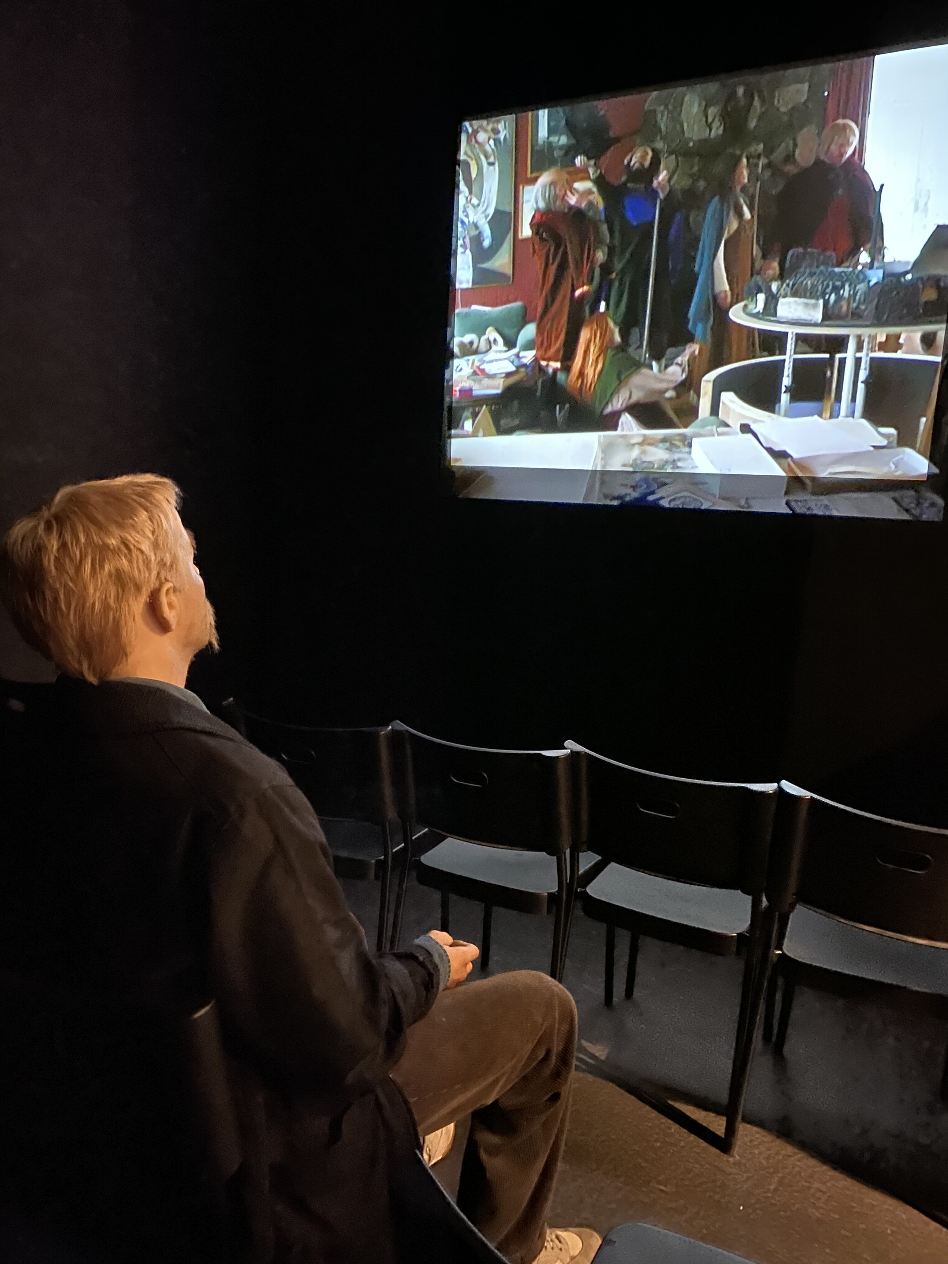 a man sitting in a chair watching a screen