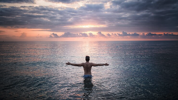 a man standing in the water with his arms out