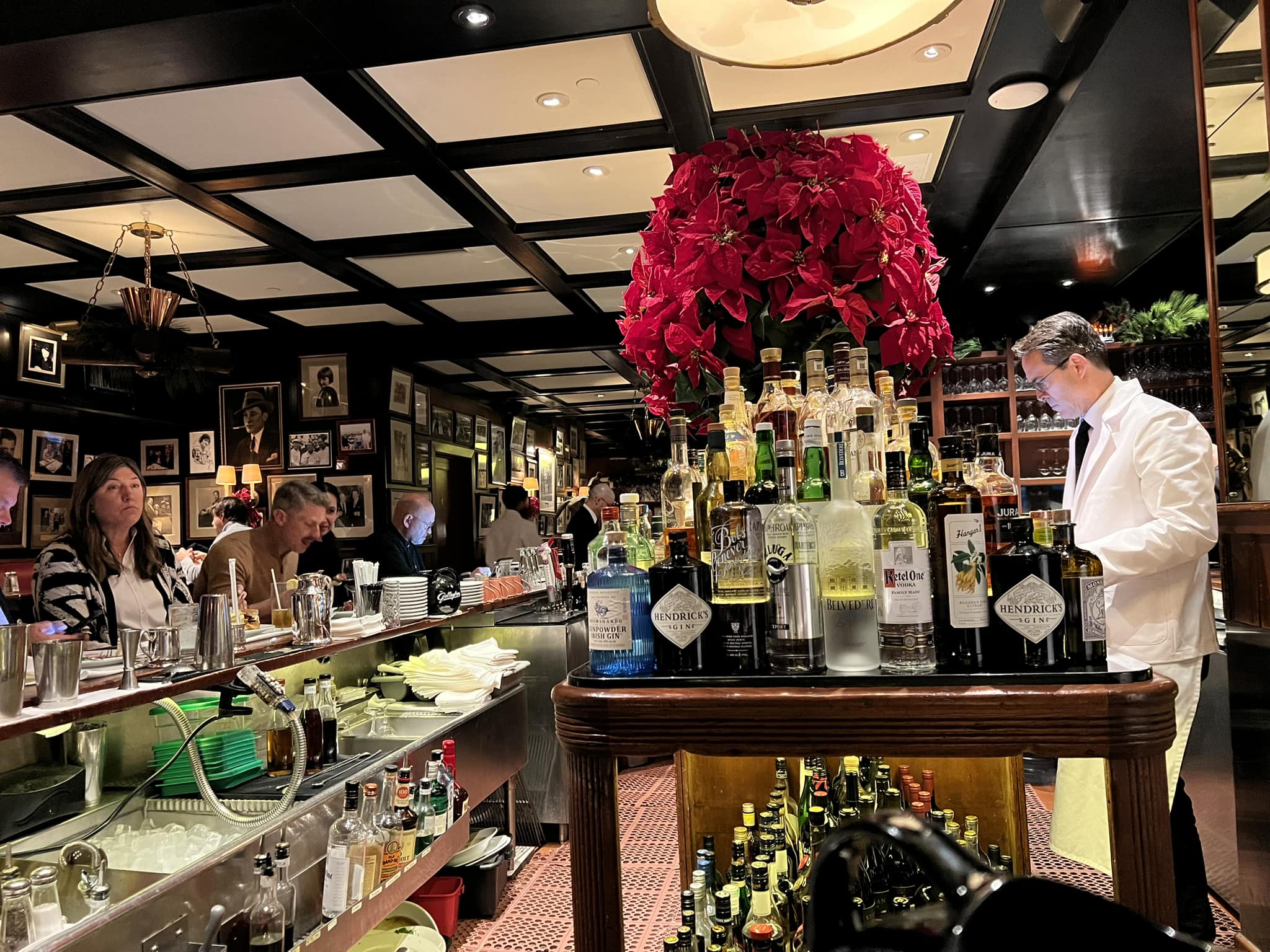 a man standing behind a bar with bottles of alcohol