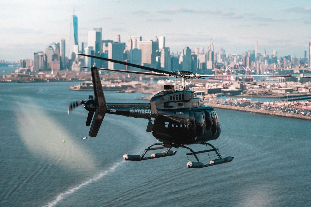 a helicopter flying over water with city in the background