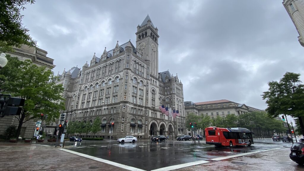 a large building with a clock tower and a red bus