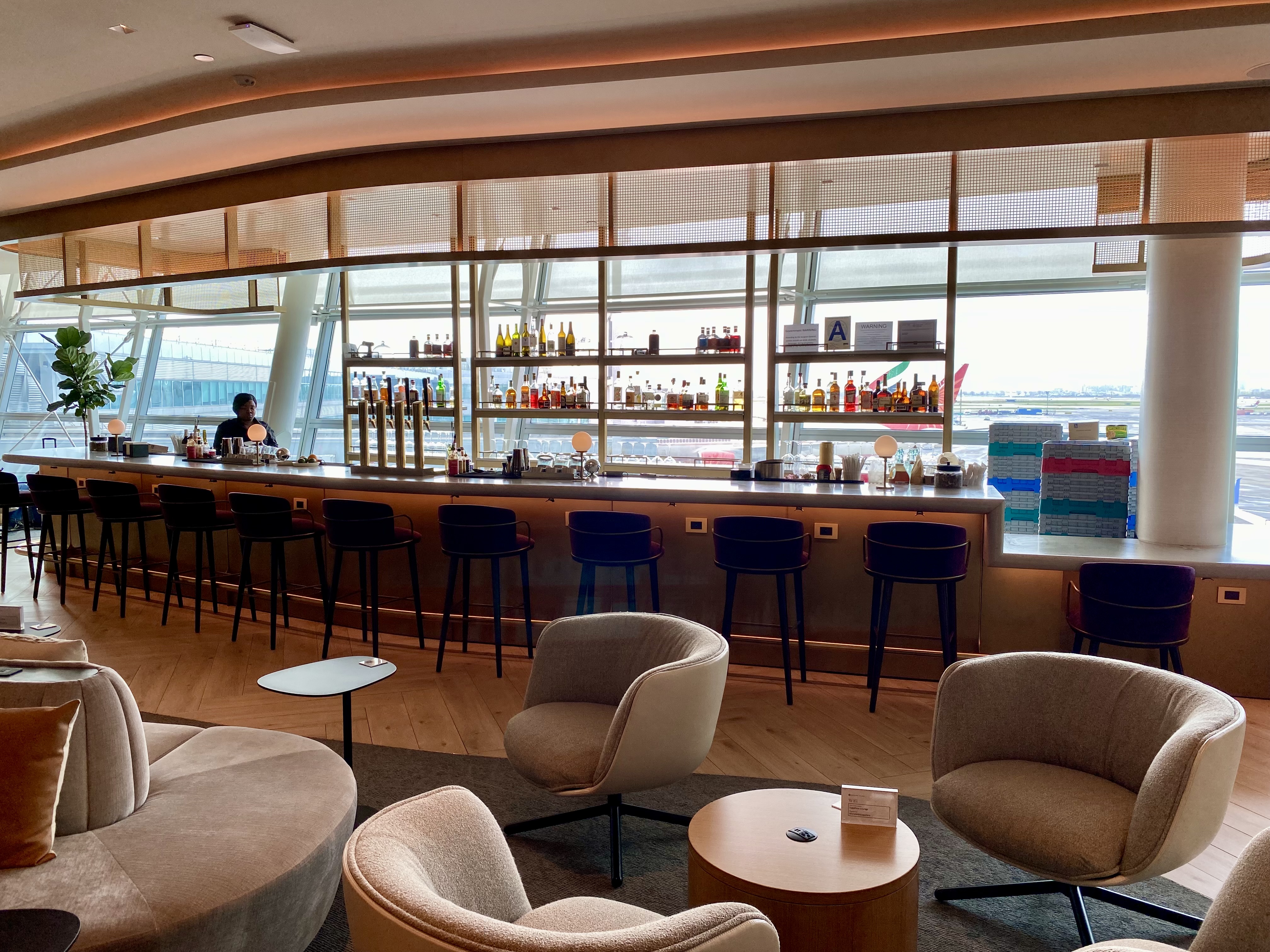 a bar with chairs and a man sitting at the counter