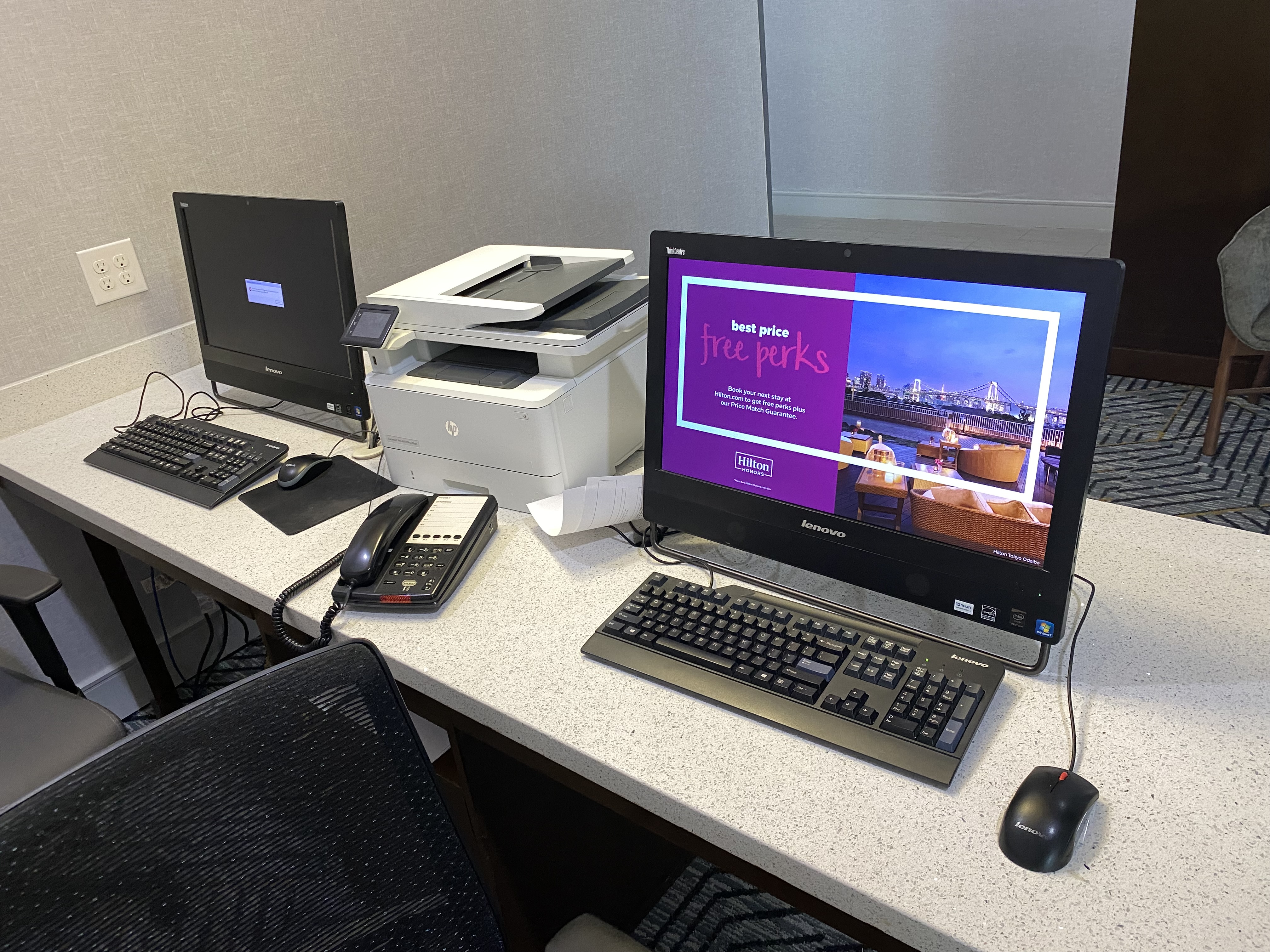 a desk with computers and a printer