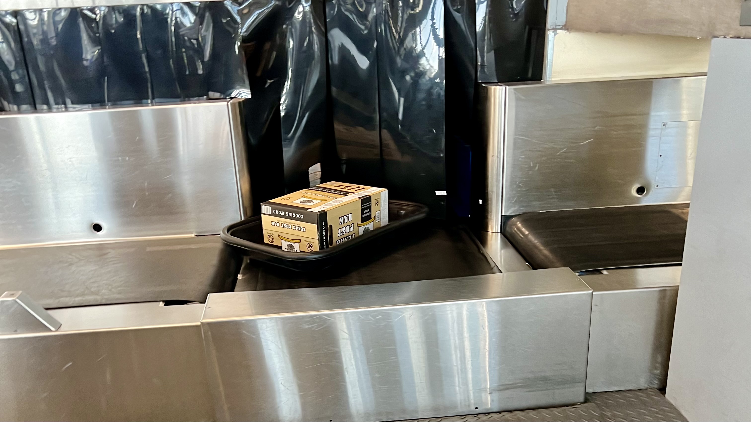 a metal luggage conveyor belt with a box on it