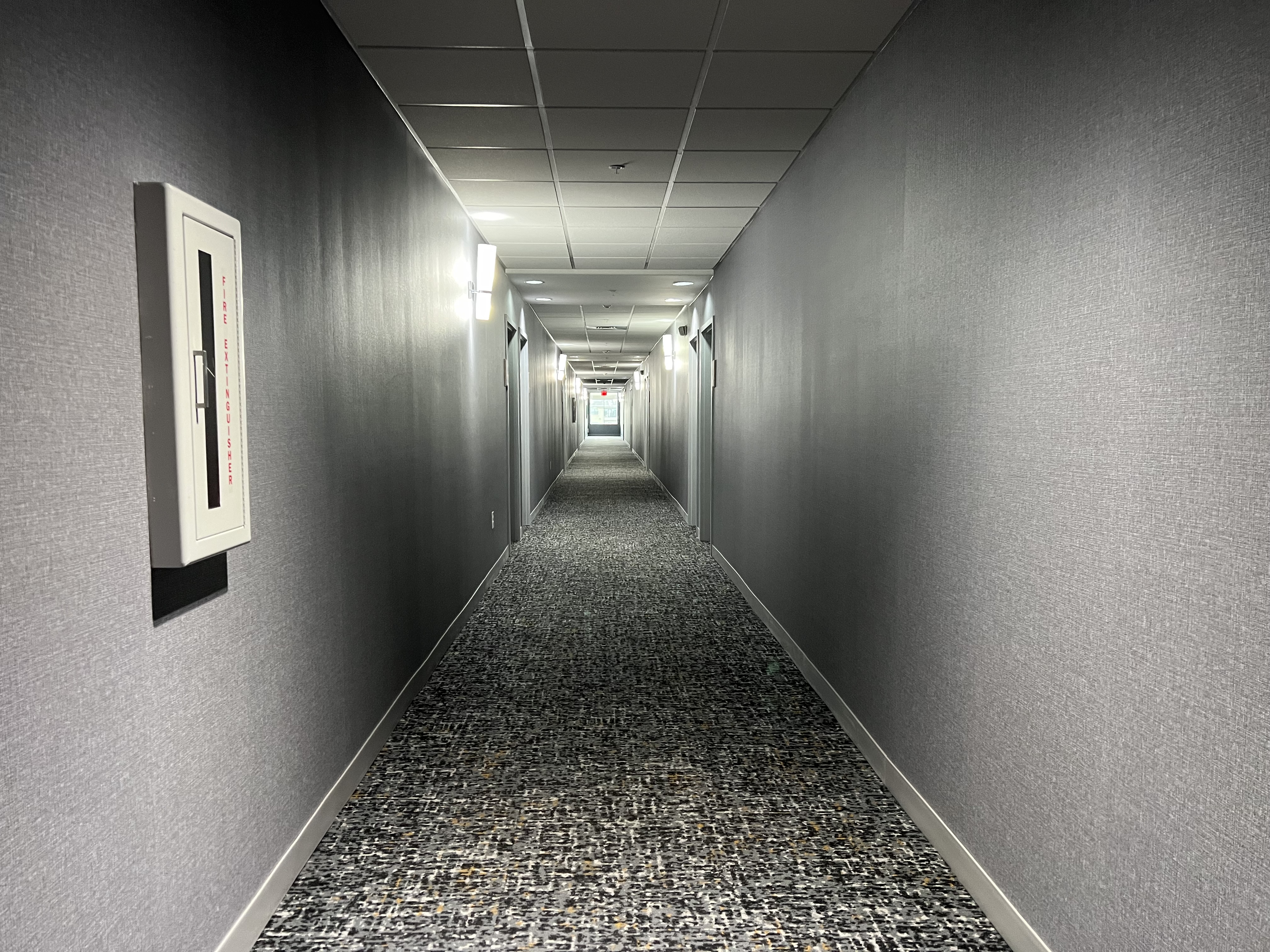 a long hallway with grey walls and a carpeted floor