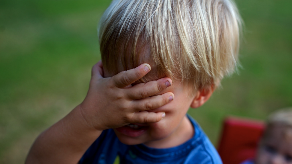 a child covering his face with his hand