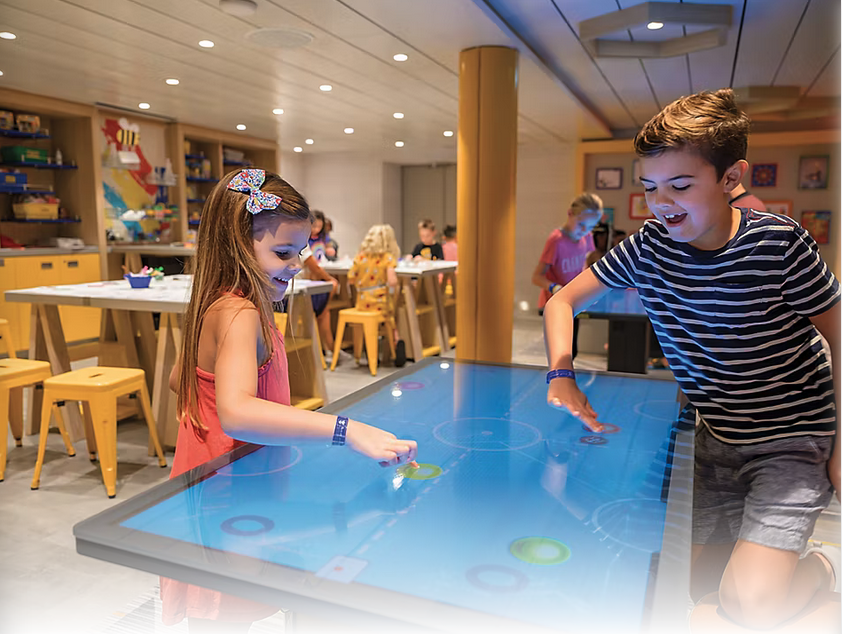 a boy and girl playing on a touch screen table